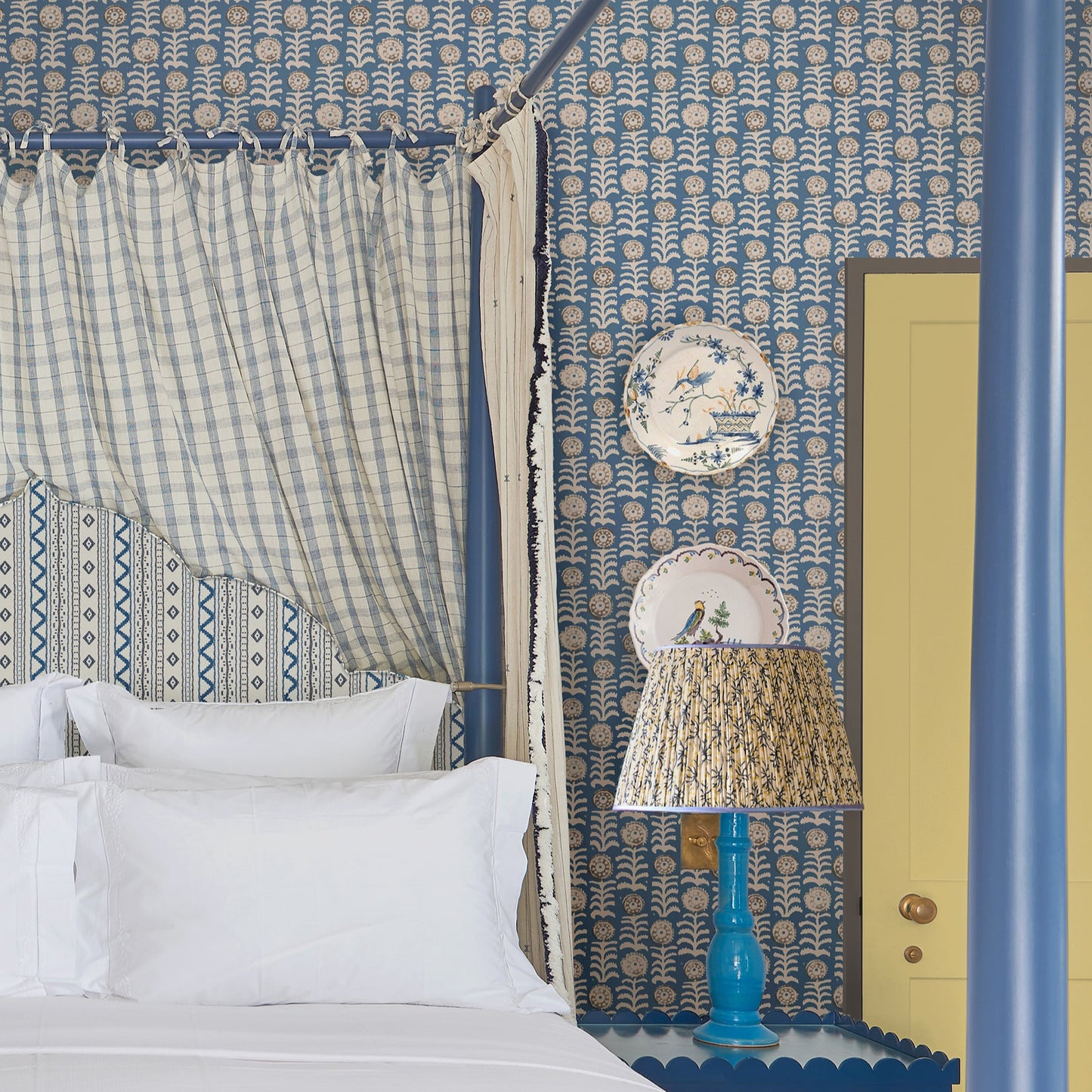 Decorative bedroom with patterned wallpaper, canopy bed, and lamp.